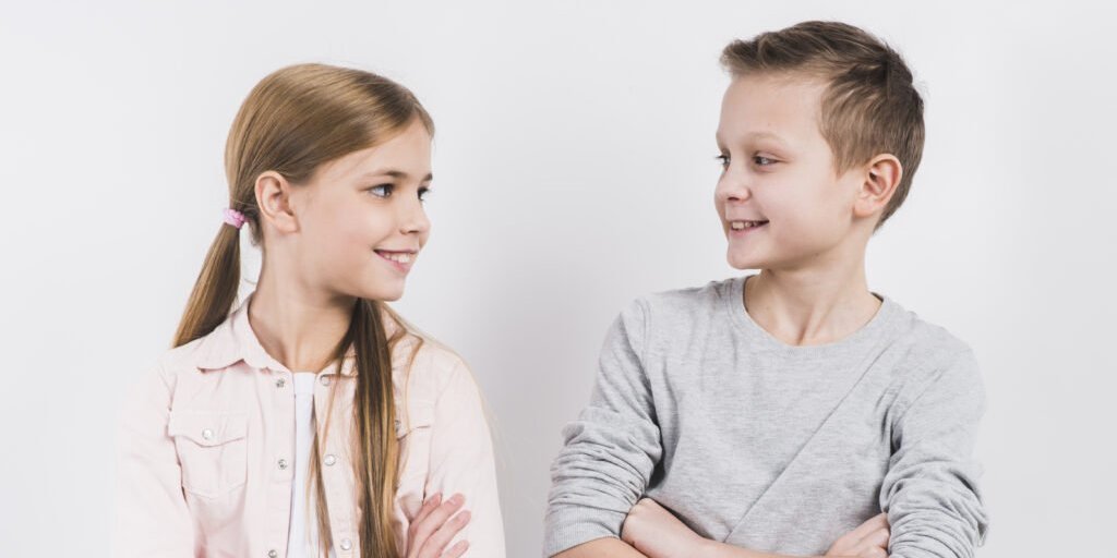 Mädchen und Junge sitzen nebeneinander und unterhalten sich