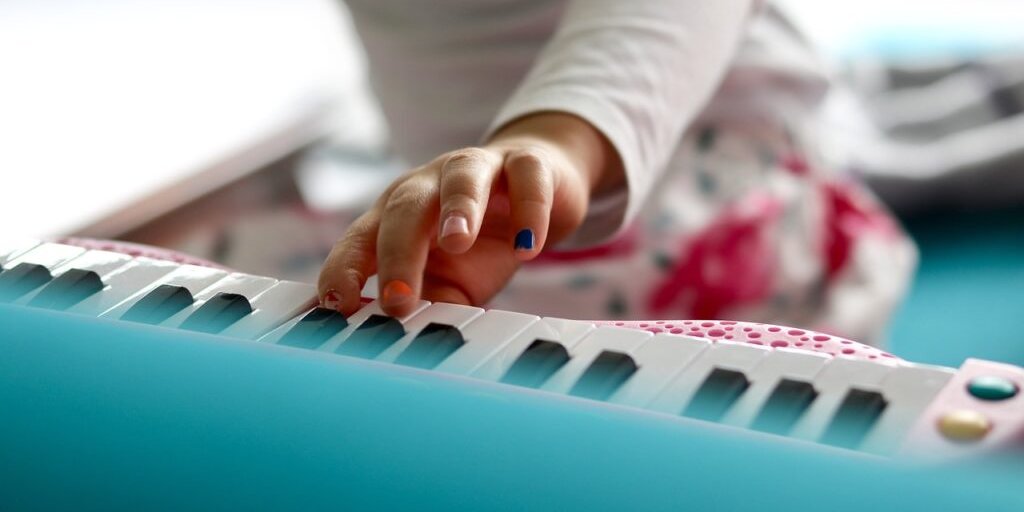 Kinderhand spielt auf den Tasten eines bunten Keyboards