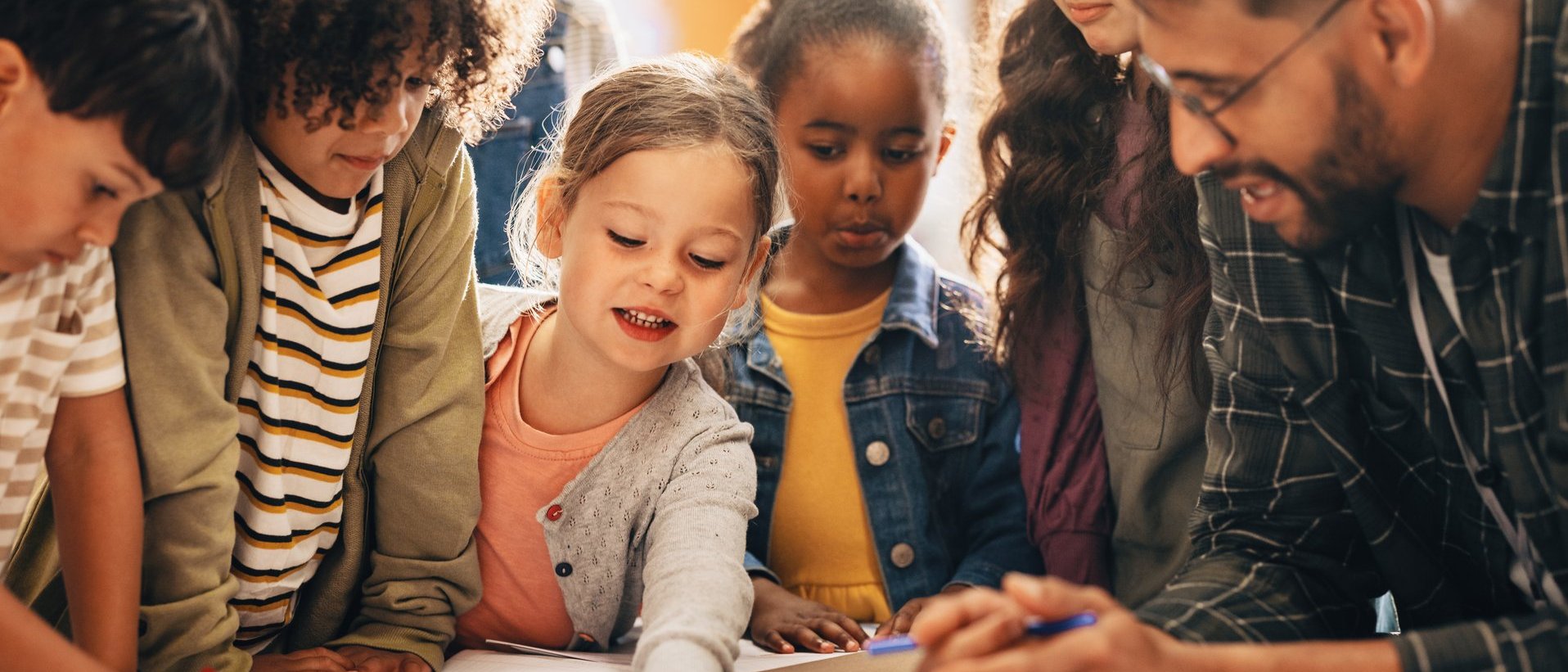Kinder und Erwachsene arbeiten gemeinsam an einem Tisch mit Papier und Stiften